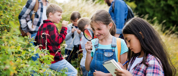 Nature Detectives Young girls observing nature with magnifying glass