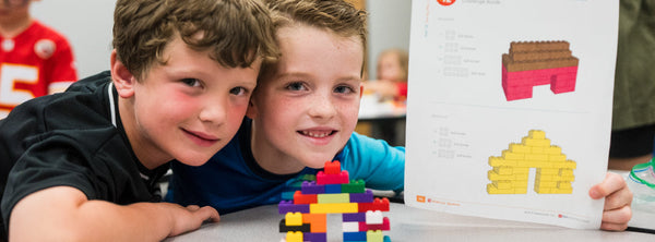 two boys proudly displaying their brick build